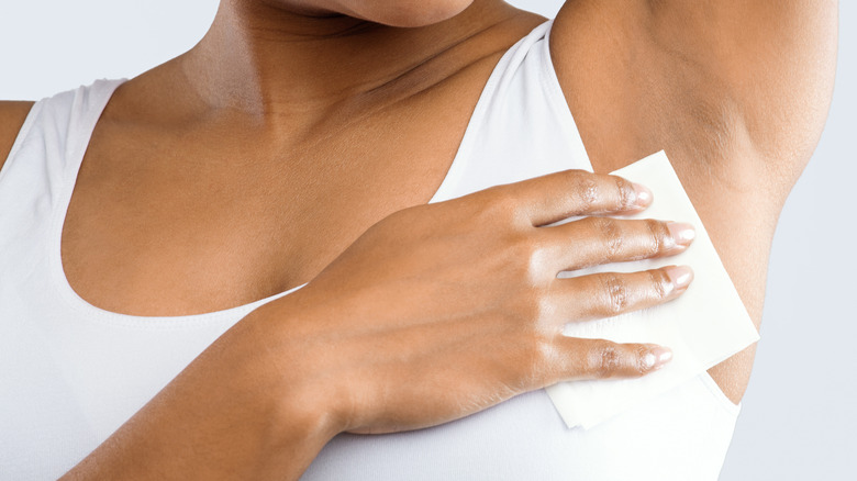 Smiling woman wiping down her underarm with a cloth