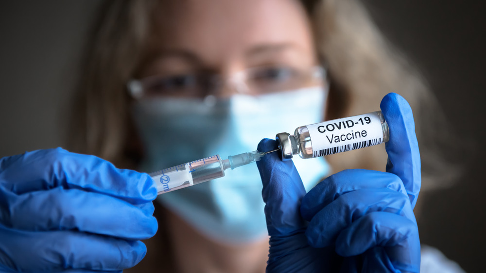 Woman holding up COVID vaccine