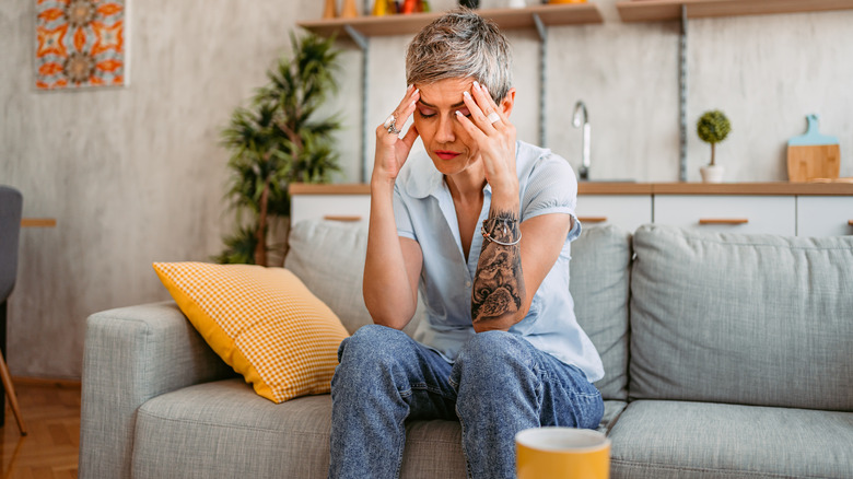 woman sitting on couch holding her head