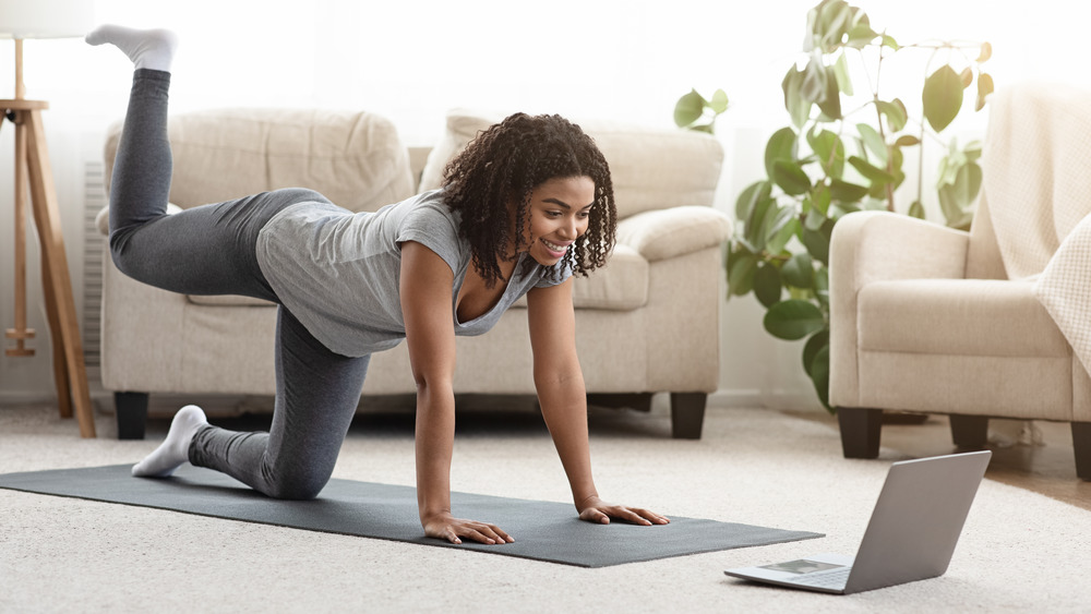 Stock photo of a young woman striking a yoga pose watching an online class