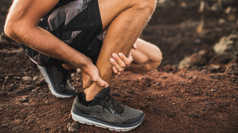 Man holding Achilles tendon with hands 