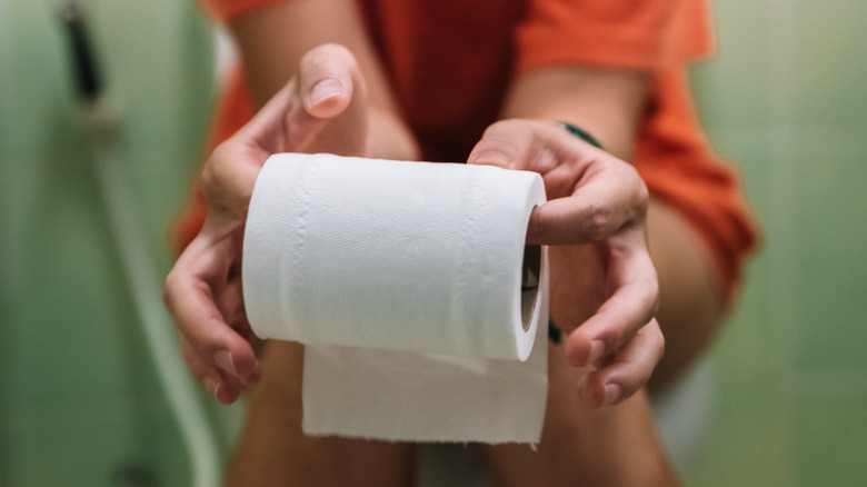 woman on toilet holding toilet paper