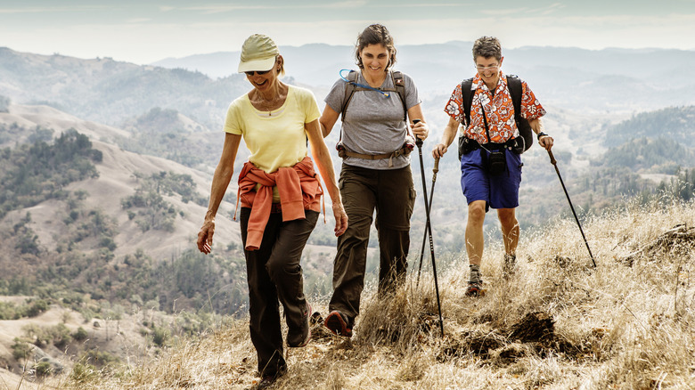 Three older women using hiking poles along a hiking trail