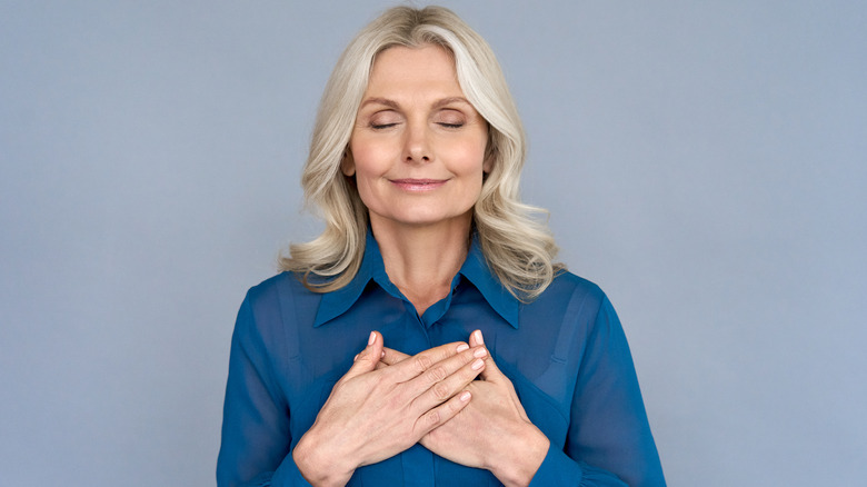 middle aged woman meditating with hands on heart