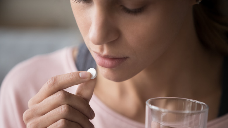 woman taking a pill with glass of water