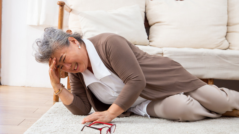 elderly Asian woman on floor grabbing her head