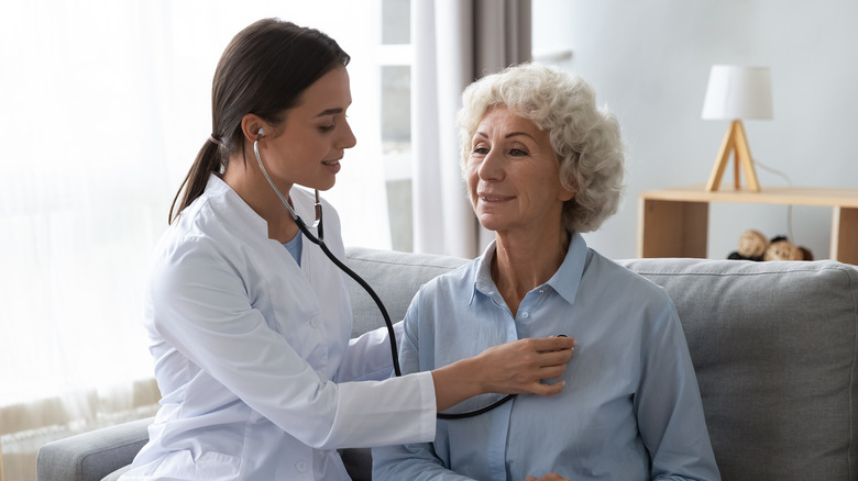 doctor with stethoscope examining older woman