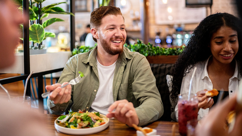 man eating a healthy salad with friends