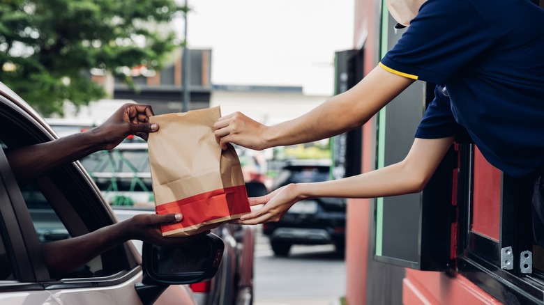 man getting fast food bag from chain restaurant worker