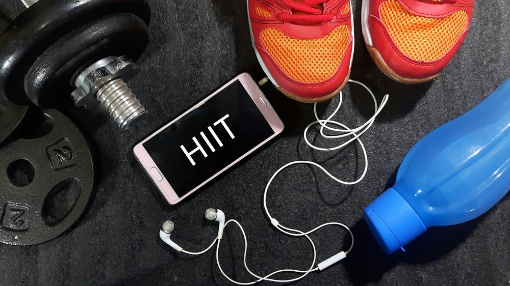 Weights, water bottle, sneakers, cell phone with letters HIIT on it