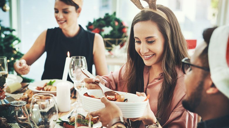 A young woman wearing antlers dipping a serving spoon into a holiday dish