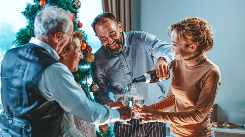 A man surrounded by family pouring champagne into glasses