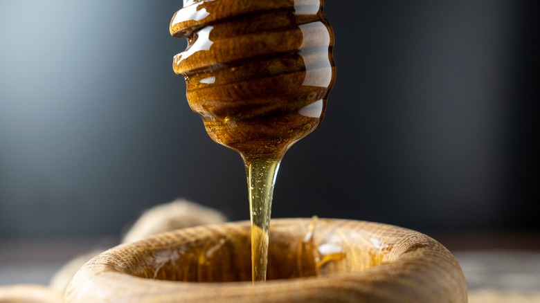 honey drzzling into wooden pot