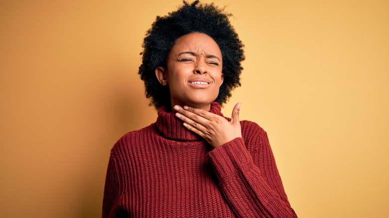 Woman in pain, holding her throat with one hand