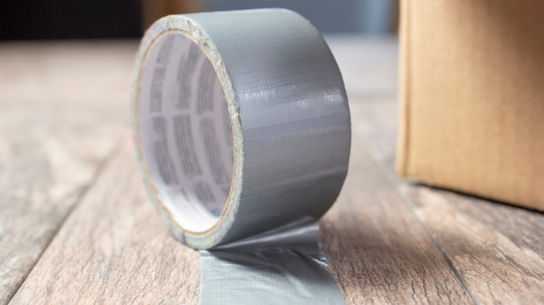 A roll of sliver duct tape slightly unrolled against a white background