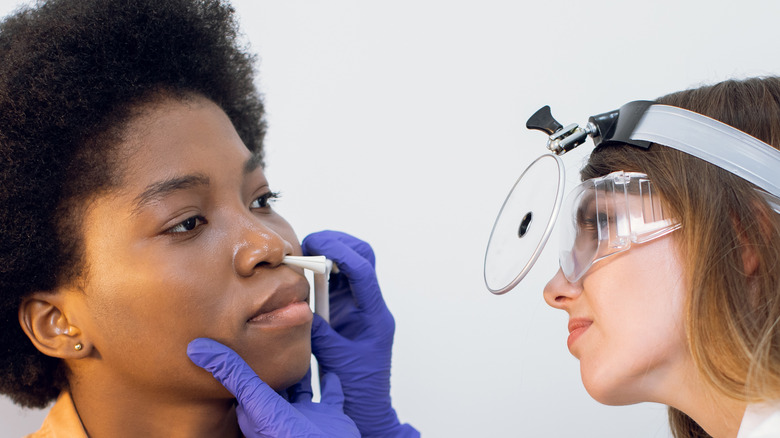 Doctor looks into patient's nose in the exam room