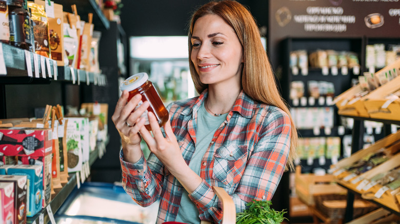 woman looking at the label of a jar of honey