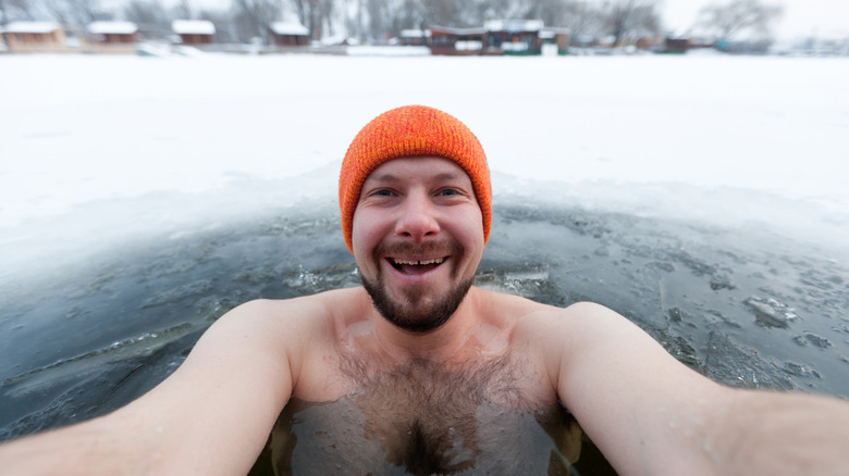 man smiles and takes a selfie in an outdoor ice bath