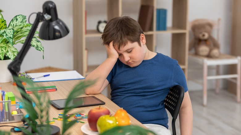 Sleepy child with tablet at desk