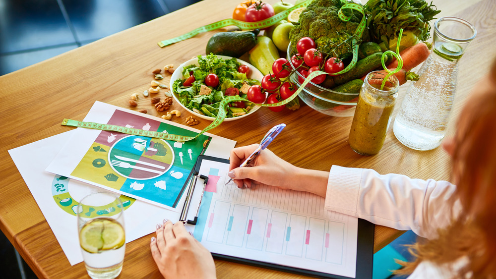 Dietitian with vegan food and measuring tape. 