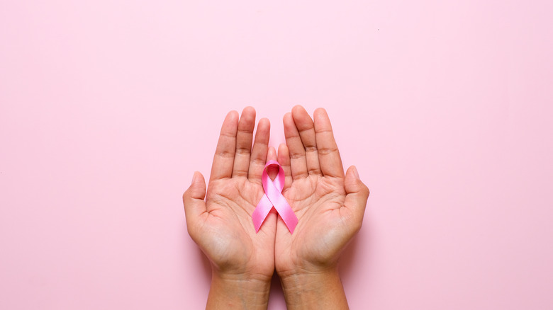 Someone holds a pink breast cancer ribbon