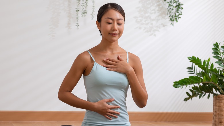 woman doing breath practices while touching her chest and belly