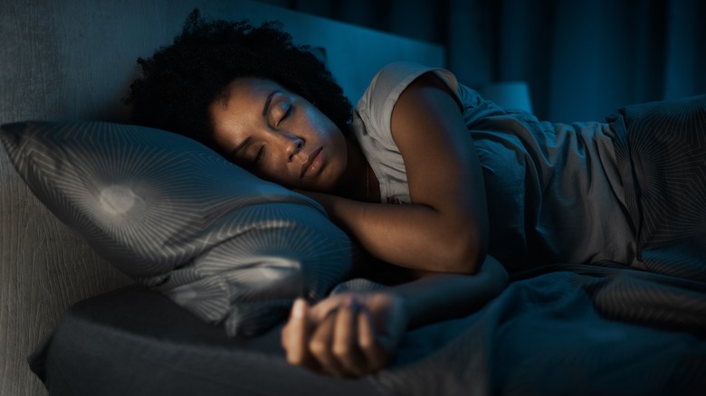 Woman asleep on her side in bed at night