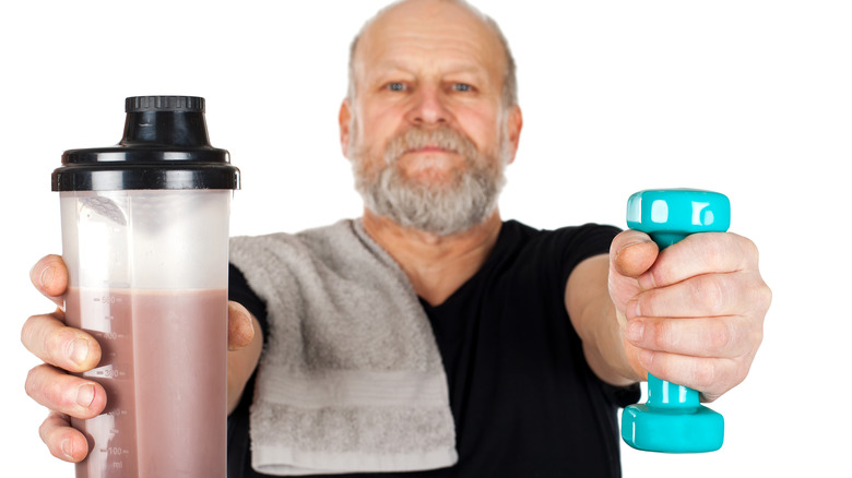 senior man holding protein shake and weight