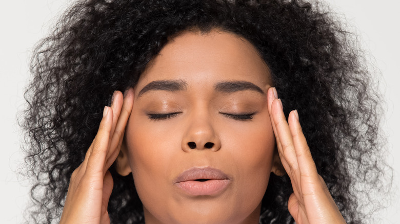 Woman exhaling with fingers to temples