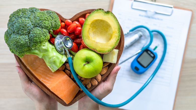 stethoscope in heart-shaped bowl with healthy foods