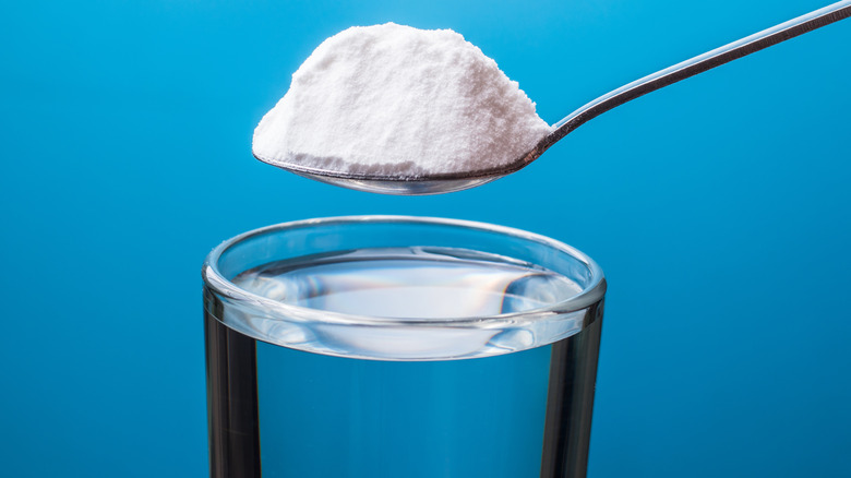 Spoonful of baking soda over water glass