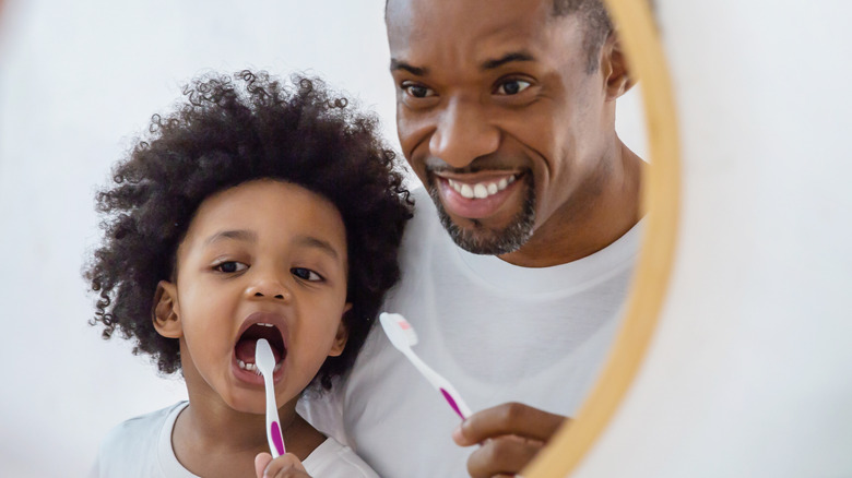 african father teaching son to brush