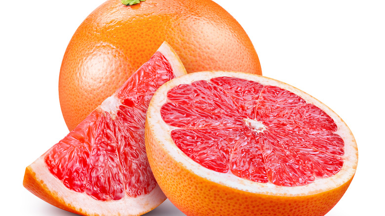 Pink grapefruit whole, half, and slice on white background