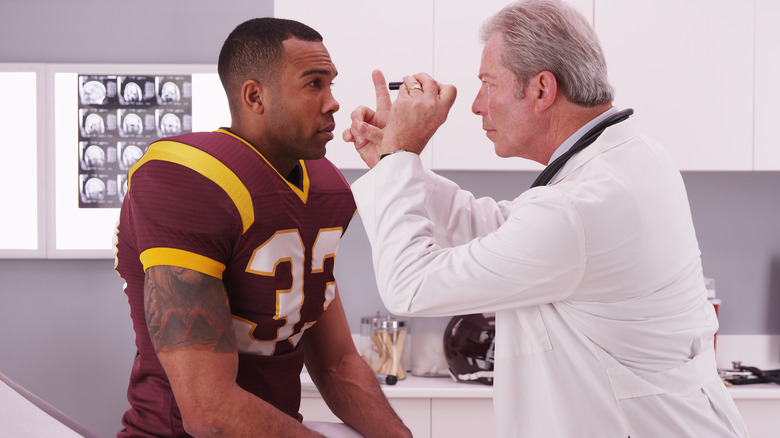 doctor checking a football players eyes 