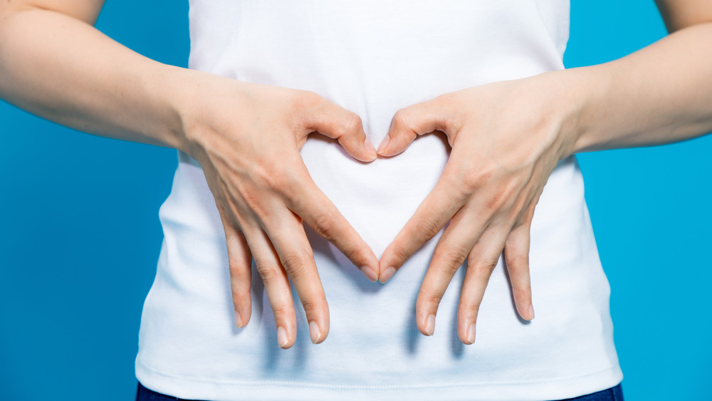 Woman making heart shape with hands on her stomach