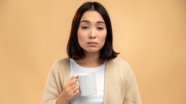 woman feeling groggy with a cup of coffee