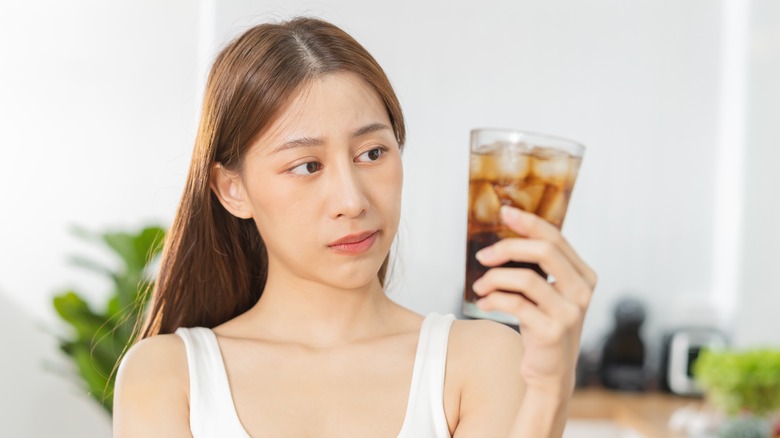 woman concerned holding soda
