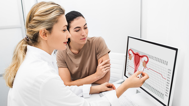 Two women looking at computer screen with menstrual cycle chart