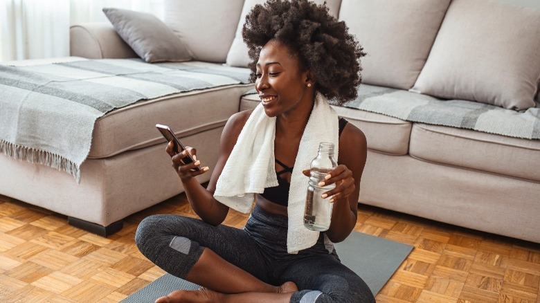 woman holding phone and water bottle