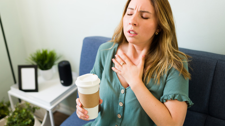 Woman holding coffee with hand to chest