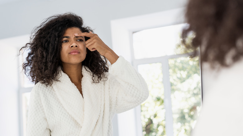 Woman examining wrinkle on face