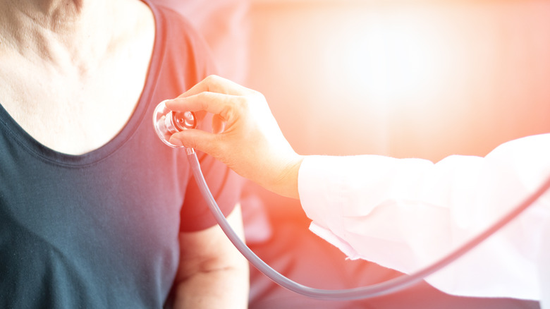 doctor using stethoscope on elderly person