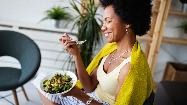 woman smiling while eating a healthy salad