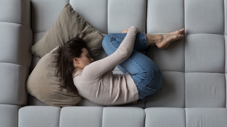 women curled up on couch depressed