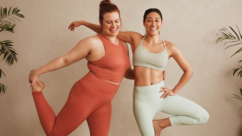 two women in workout clothes with arms around each other 