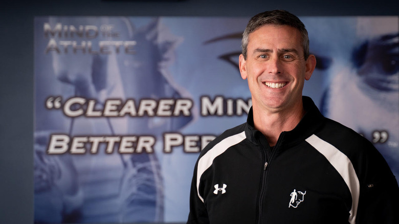 Dr. Jarrod Spencer standing in front of a promo sign for his book