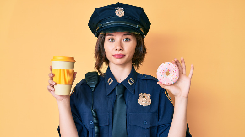 female police officer holding donut and coffee