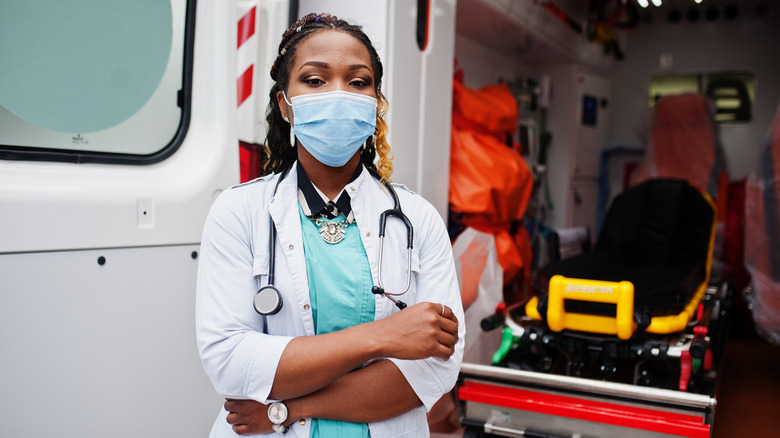 An EMT stands at the back of her ambulance