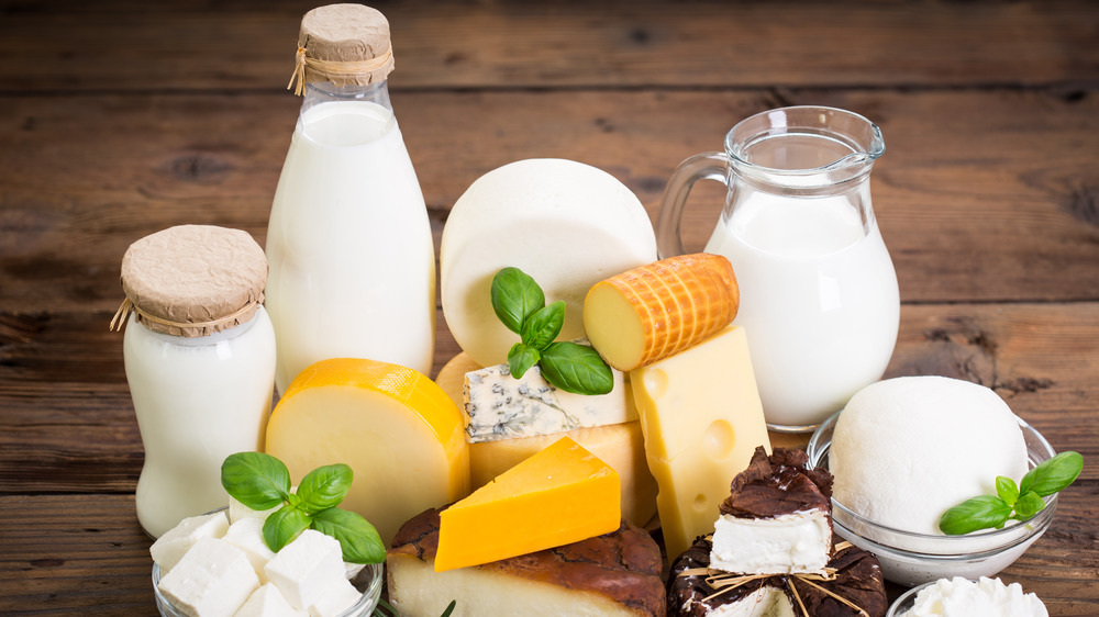 Various dairy products including milk and cheese on a cutting board
