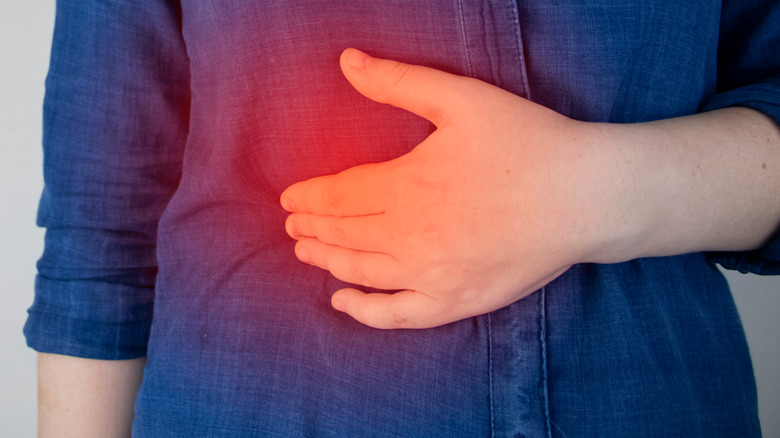 Hand touching their inflamed stomach: Crohn's disease concept